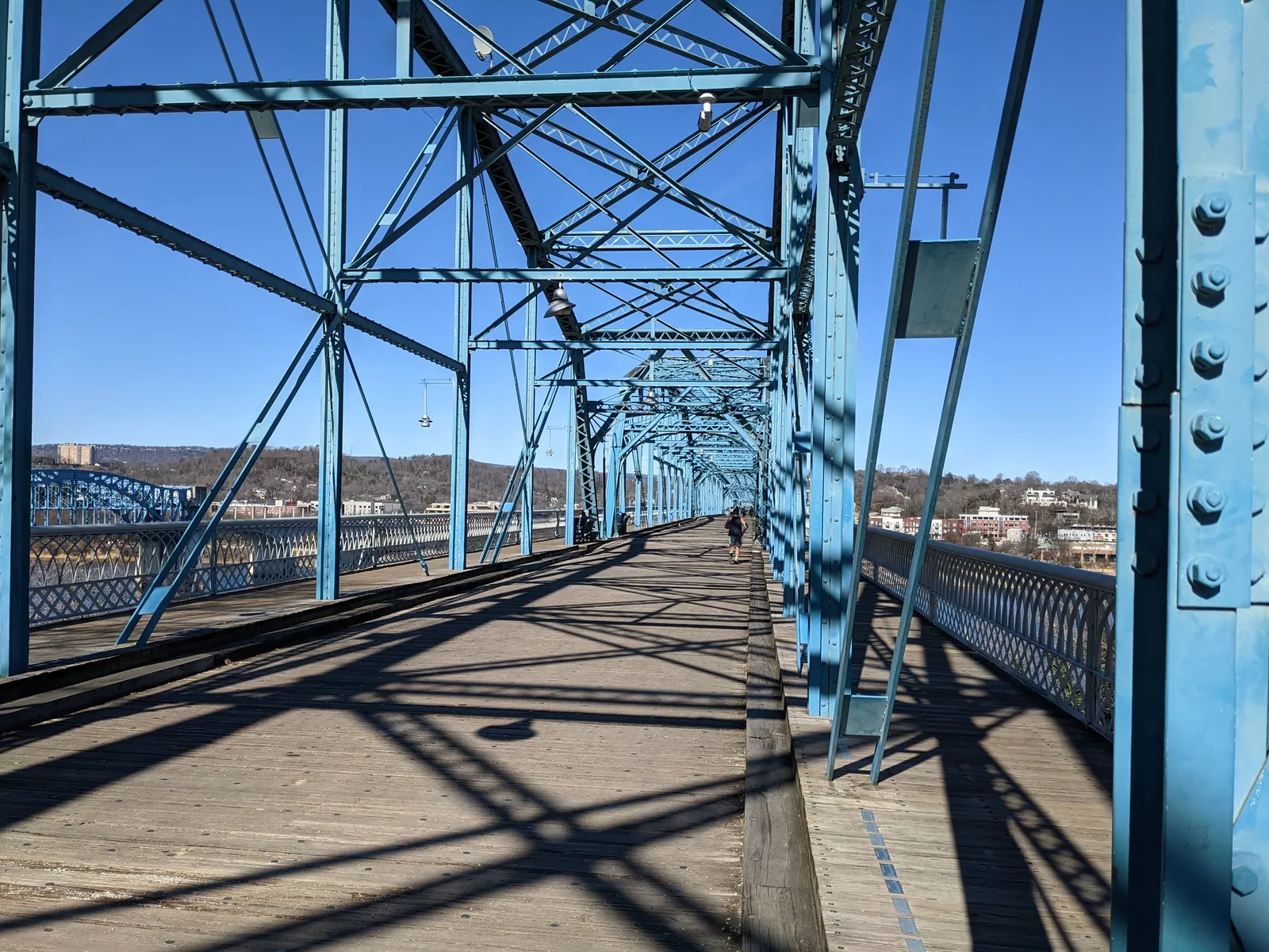 Wooden pedestrian deck and blue steel trusses of the Walnut Street Bridge on a sunny day in Chattanooga